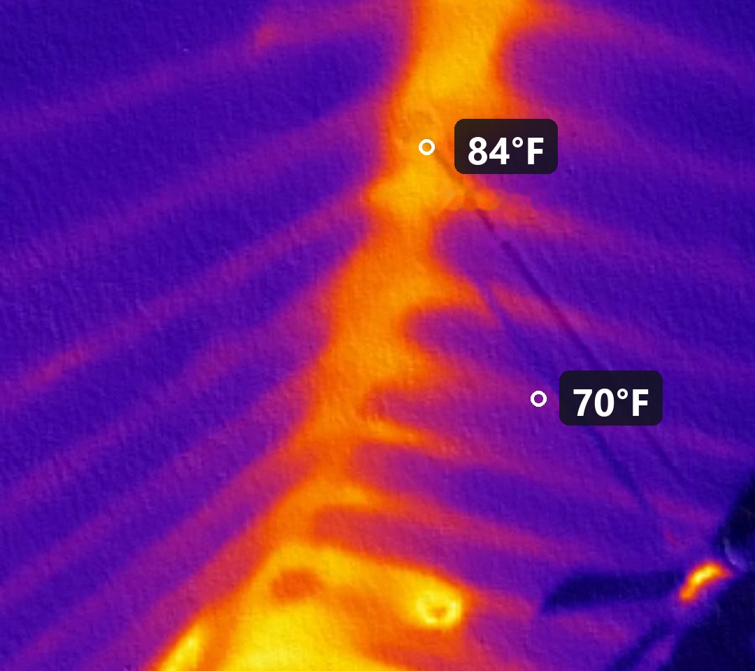 Thermal camera scan of a ceiling showing an 84°F strip where attic insulation was pushed aside next to 70°F insulated ceiling
